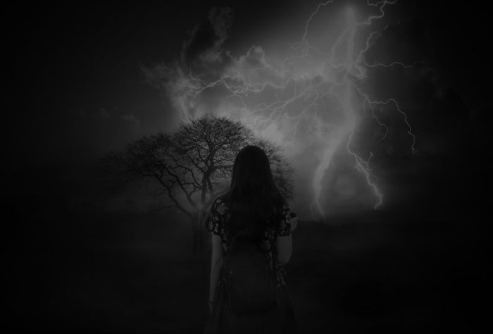 An image of a woman facing away looking toward a stormy sky