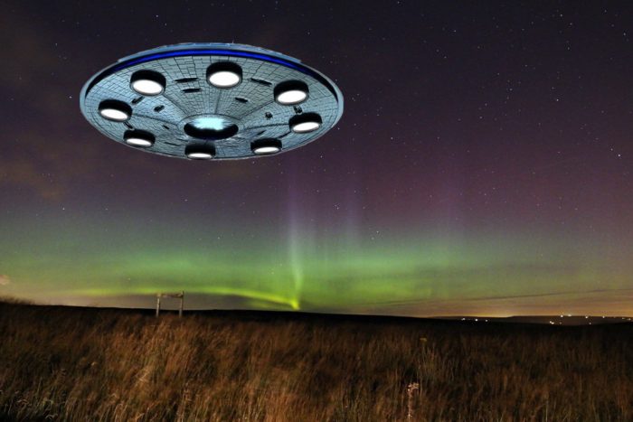 A flying saucer superimposed onto a picture of a field at night