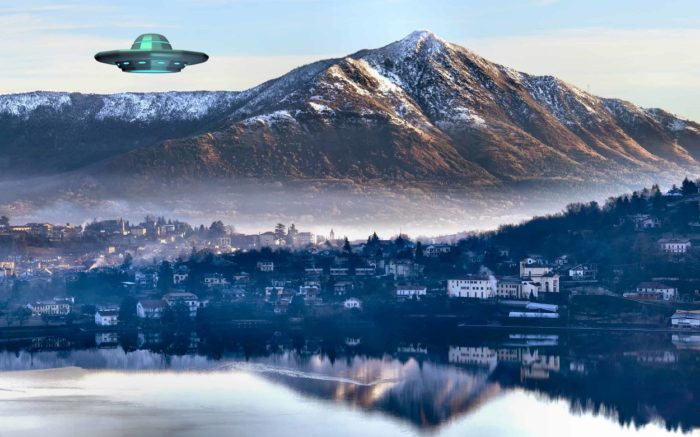 A UFO superimposed into a picture of a village with a mountain in the background