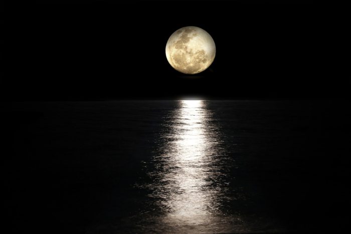 The reflection of the Moon on the water with a full moon overhead