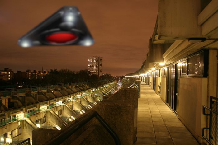A triangular UFO hovering over a housing estate at night