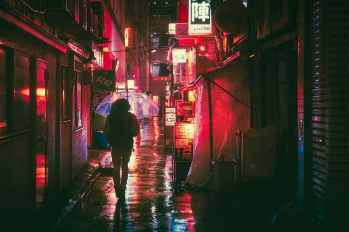 A picture of a person walking down a Japanese street at night