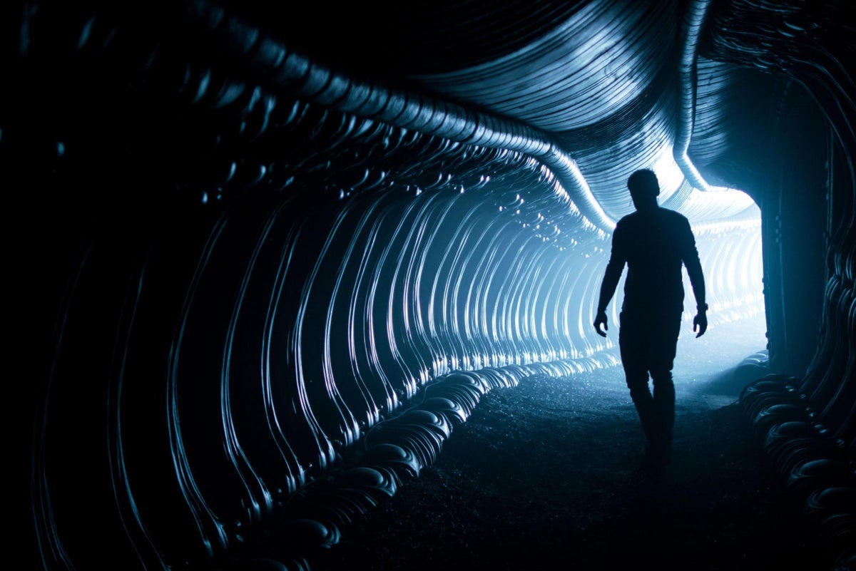 A dark figure working through a tunnel