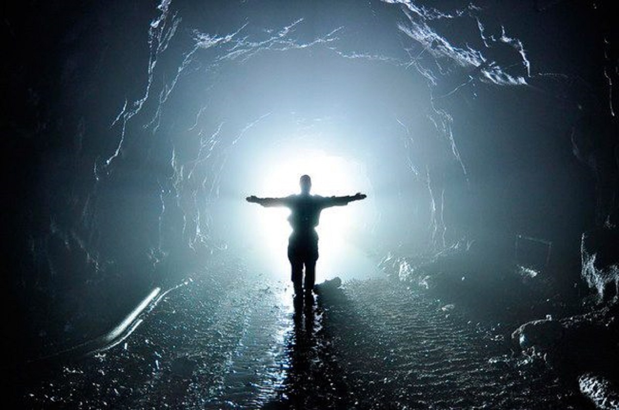 A person stood in a tunnel with a light behind them