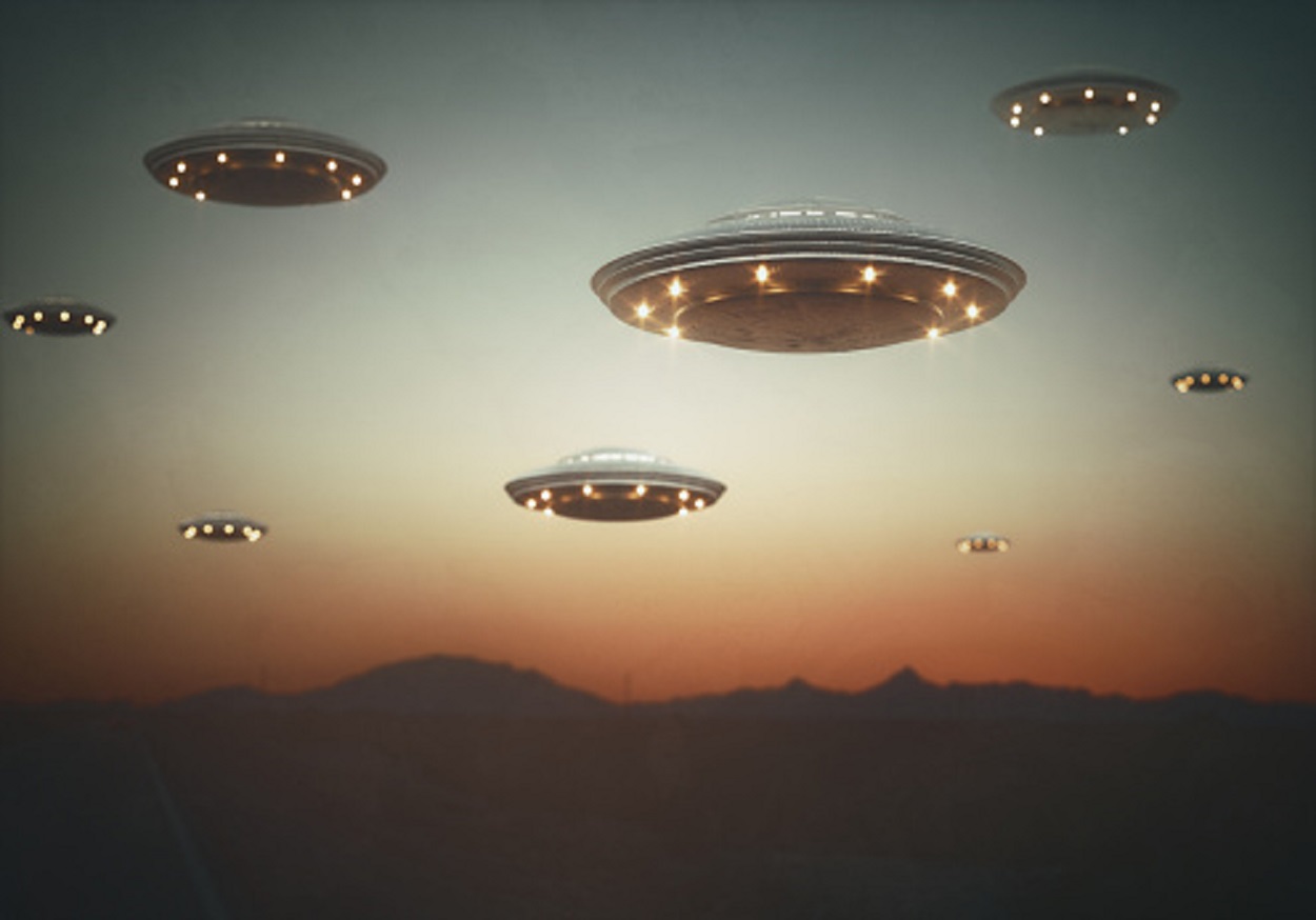 A depiction of several UFOs in the dusk sky