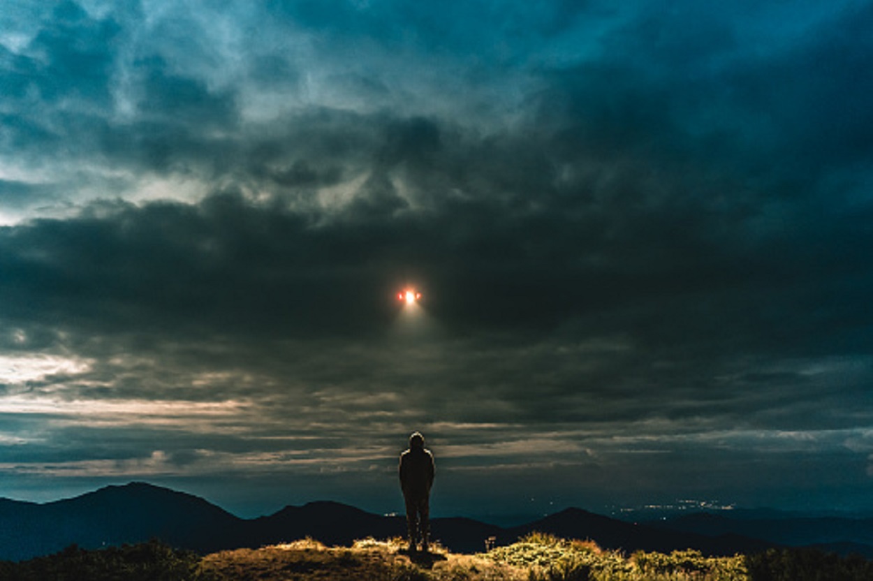 A depiction of a man looking up at a strange light